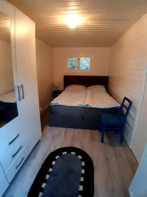 a small bedroom with a bed and a chair at Koselig blått hus - utsikt Losna in Tretten