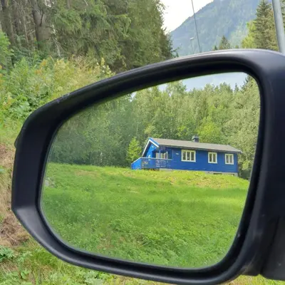 a view of a blue house in a rear view mirror at Koselig blått hus - utsikt Losna in Tretten