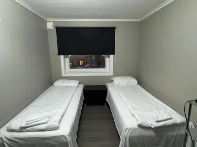 two beds in a small room with a window at Ålesund room with shared shower in Ålesund