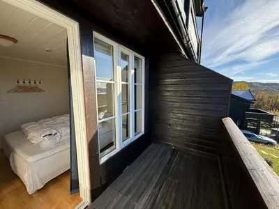 a balcony of a house with a bed and a window at Charming Getaway ,Near Ski Trails And Hiking Paths in Beitostøl