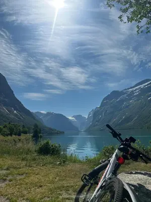 a bike parked next to a lake with mountains at Huset Vårt - Bed and Breakfast in Hornindal