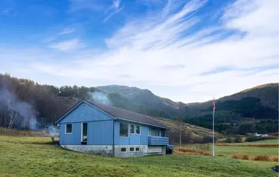 a blue house in a field with mountains in the background at 3 Bedroom Nice Home In Mjosundet in Ertvåg