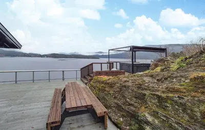 a wooden bench sitting on the side of a lake at Amazing Home In Omastrand With Wifi in Gjuvsland