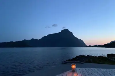 a lantern sitting on the shore of a body of water at Exclusive fjord getaway with sauna in Leirgulen