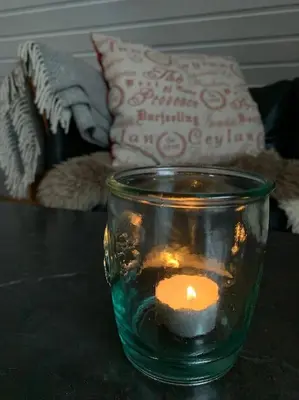 a candle in a glass jar on a table at Exclusive fjord getaway with sauna in Leirgulen