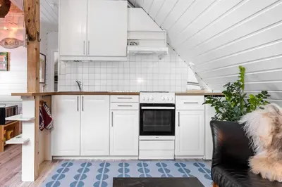 a kitchen with white cabinets and a dog sitting on a couch at Exclusive fjord getaway with sauna in Leirgulen