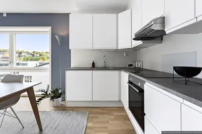 a kitchen with white cabinets and a dining table at Eksklusiv byleilighet med utsikt i Trondheim Sentrum in Trondheim