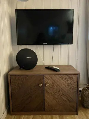 a flat screen tv on top of a wooden cabinet at Pen hytte nær Ål in Liagardane