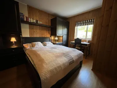a bedroom with a bed and a desk and a window at Cozy Getaway Sauna and Terrace in Beitostøl