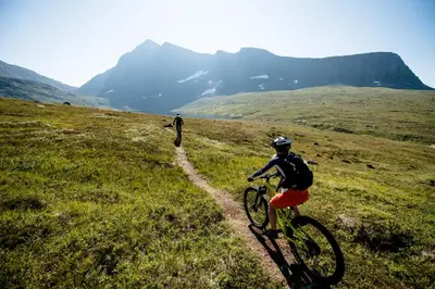 two people riding bikes on a grassy hill at Phillipshaugen Lodge in Øksendalsøra