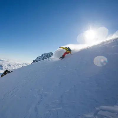 a person riding a snowboard down a snow covered slope at Charming cabin Near Jotunheimen Trails in Beitostøl