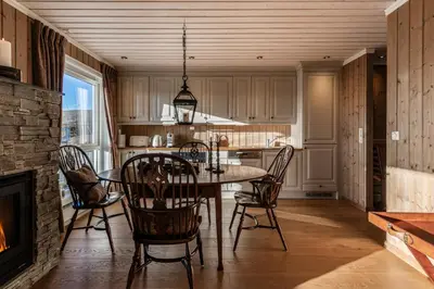 a kitchen with a table and chairs and a fireplace at Kikut Panorama Geilo Ski-in Ski-out in Geilo