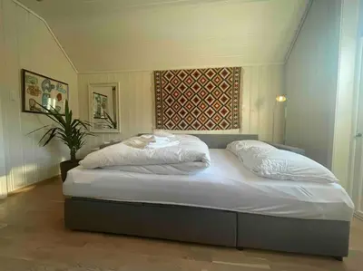 a bedroom with a large bed with white sheets at Idyllisk hus i Vassenden sentrum in Vassenden