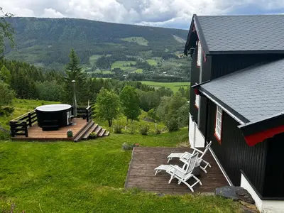 a house with a deck with chairs and a gazebo at Unikt gårdshus - Gamlestua in Vestre Gausdal