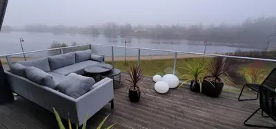 a couch on a balcony with a view of a lake at Unique 3-Storey House in Trysil Luxury Living in the Heart of the Village in Trysil