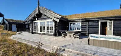 a log cabin with a hot tub on a deck at The Whole Beautiful Cabin With Jacuzzi A Luxurious Getaway in Solberglia in Østby