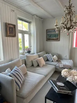 a living room with a couch and a chandelier at Exclusive 1920 century villa 10 min from AirPort in Malvik