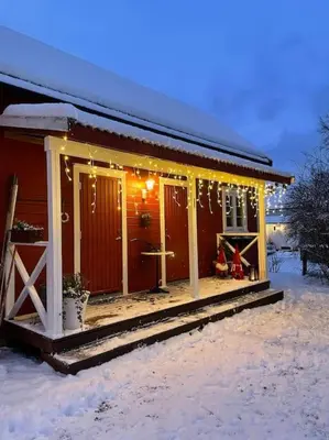 a house with a porch in the snow with lights at Exclusive 1920 century villa 10 min from AirPort in Malvik