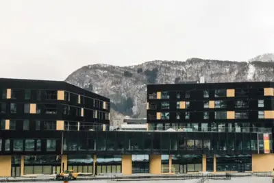 a large building with a mountain in the background at Toppleilighet på elvekanten med to romslige soverom in Førde