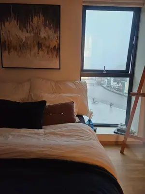 a bedroom with a bed and a large window at Toppleilighet på elvekanten med to romslige soverom in Førde