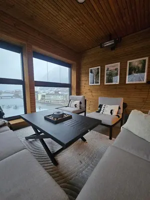 a living room with a table and two couches and windows at Toppleilighet på elvekanten med to romslige soverom in Førde