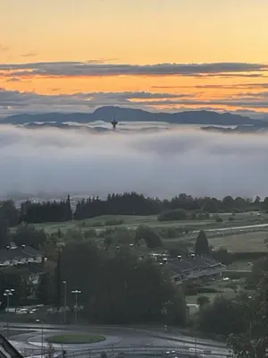 a view of a foggy city with a bridge in the background at Sjarmerende enebolig in Trondheim