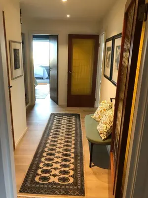 a hallway with a rug and a chair and a door at Sjarmerende enebolig in Trondheim