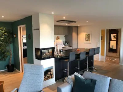 a kitchen and living room with a bar with a fireplace at Sjarmerende enebolig in Trondheim