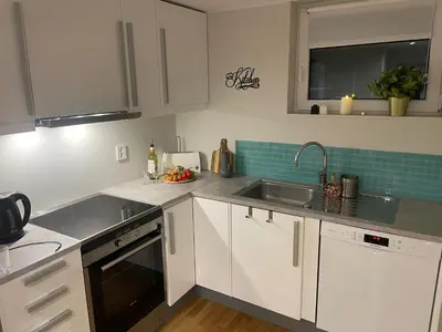 a kitchen with white cabinets and a sink at Bingo apartaments in Hønefoss