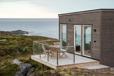 a tiny house with a balcony and a table and chairs at Runde Panorama - Blått Hav in Terøy