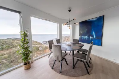 a dining room with a table and chairs and the ocean at Runde Panorama - Blått Hav in Terøy