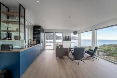 a kitchen with blue cabinets and a view of the ocean at Runde Panorama - Blått Hav in Terøy