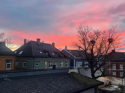 a view of a sunset from the roofs of houses at Cozy room near city centre in Trondheim