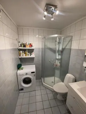 a bathroom with a shower stall and a washing machine at Cozy room near city centre in Trondheim