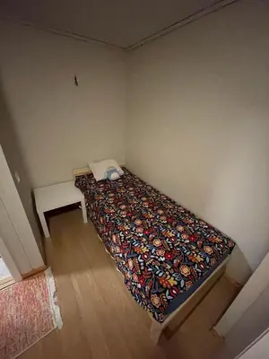 a small bedroom with a bed with a colorful blanket at Cozy room near city centre in Trondheim