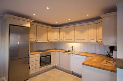 a kitchen with white cabinets and a stainless steel refrigerator at Perfectly Located With Ski Access And Sauna in Beitostøl