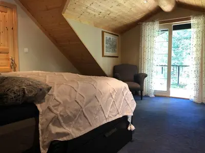 a bedroom with a bed and a chair and a window at Hytta Kalven in Lunner