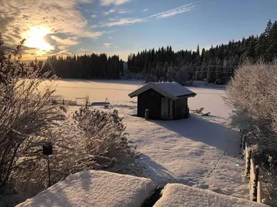 a small shed in the snow with the sun in the background at Hytta Kalven in Lunner