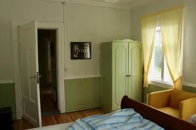 a bedroom with a bed and a chair and a cabinet at Sjarmerende hus i sentrum in Elverum
