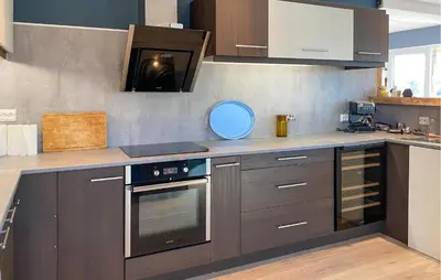 a kitchen with brown cabinets and a stove top oven at Beautiful Home In Fjørtoft With Wifi in Fjørtoft