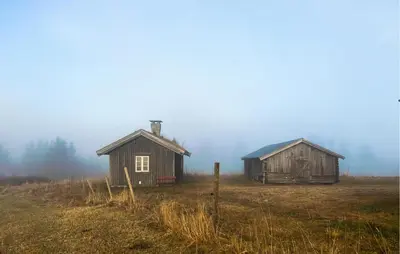 two old barns in a field in the fog at Stunning Home In Fåvang With Wifi in Favang