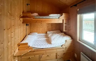 a bed in a wooden cabin with a window at Stunning Home In Fåvang With Wifi in Favang