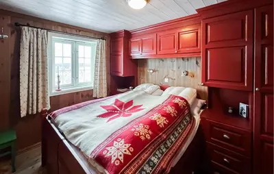 a bedroom with a bed with red cabinets and a window at Fantastisk Hytte På Lenningen in Etnedal