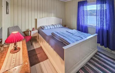 a bedroom with a bed with a red lamp and a window at 2 Bedroom Awesome Home In Vikersund in Vikersund