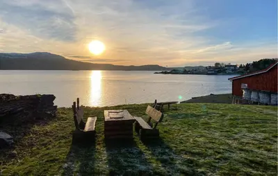 a bench sitting on the grass next to a body of water at 2 Bedroom Beautiful Home In Frosta