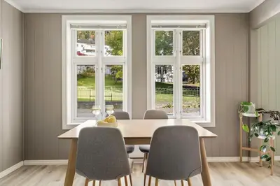 a dining room with a table and two windows at Leilighet i Sandviken in Bergen
