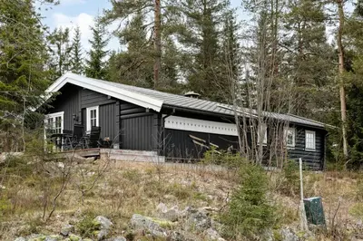 a black house in the middle of a forest at Cabin With Panoramic Views Over Trysil in Trysil