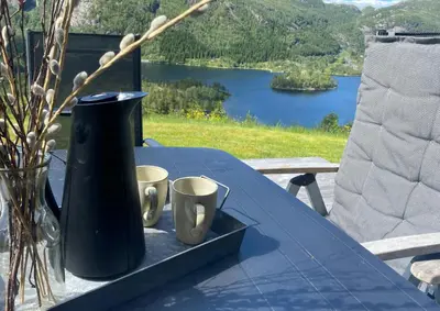 a blue table with a vase and two cups on it at Mountain Cabin With Magical View And Tranquil Lake in Matre