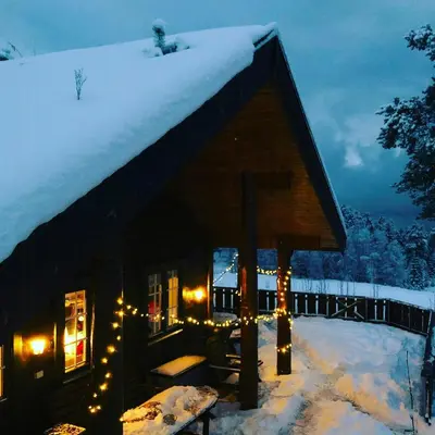 a log cabin with christmas lights in the snow at Countryside Cabin With Jacuzzi Near Stryn in Sølberg