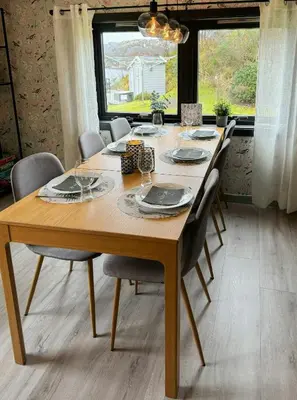 a wooden table with chairs around it in a dining room at Charming Seaside Cabin With Amazing View in Hardbakke